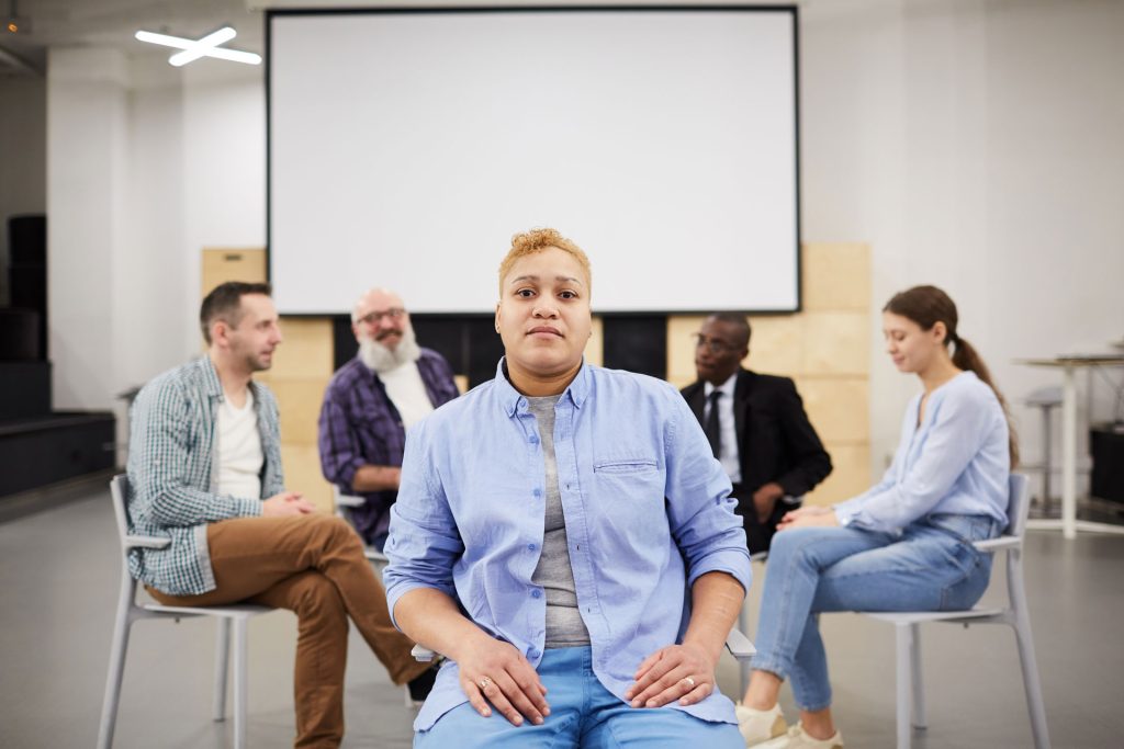 Woman looking at the camera during a group therapy.