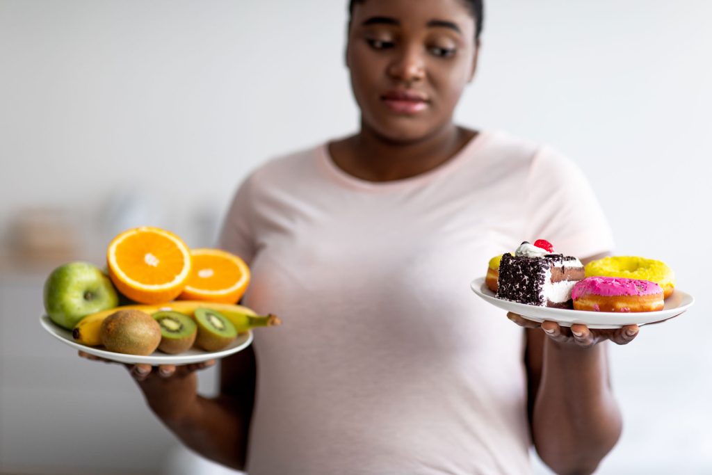 Plus size woman choosing between fruits or desserts.
