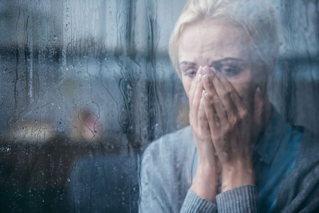Adult woman staring at glass windows sad.