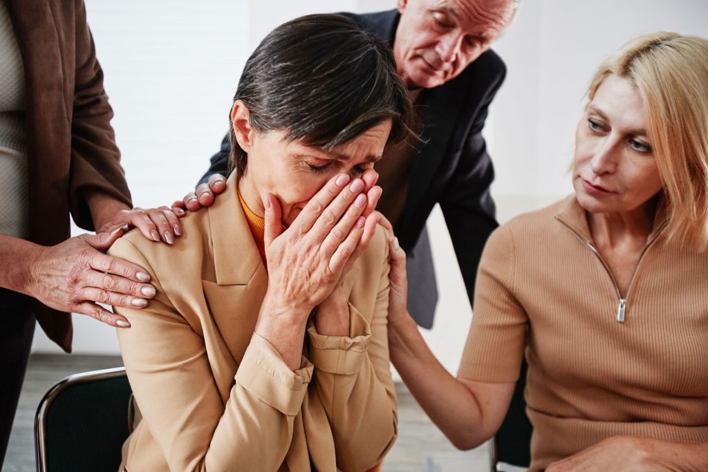 Woman crying, family console her.
